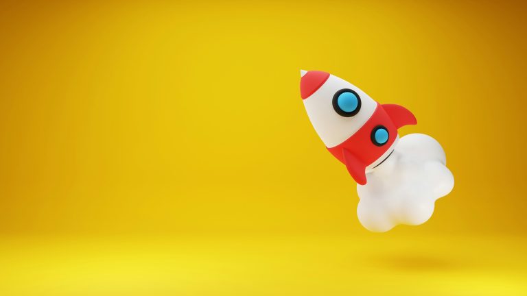 A red and white toy rocket on a yellow background blasts off. Image by Andy Hermawan.