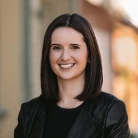 A picture of Kate May. Kate has shoulder length dark hair and is smiling at the camera.